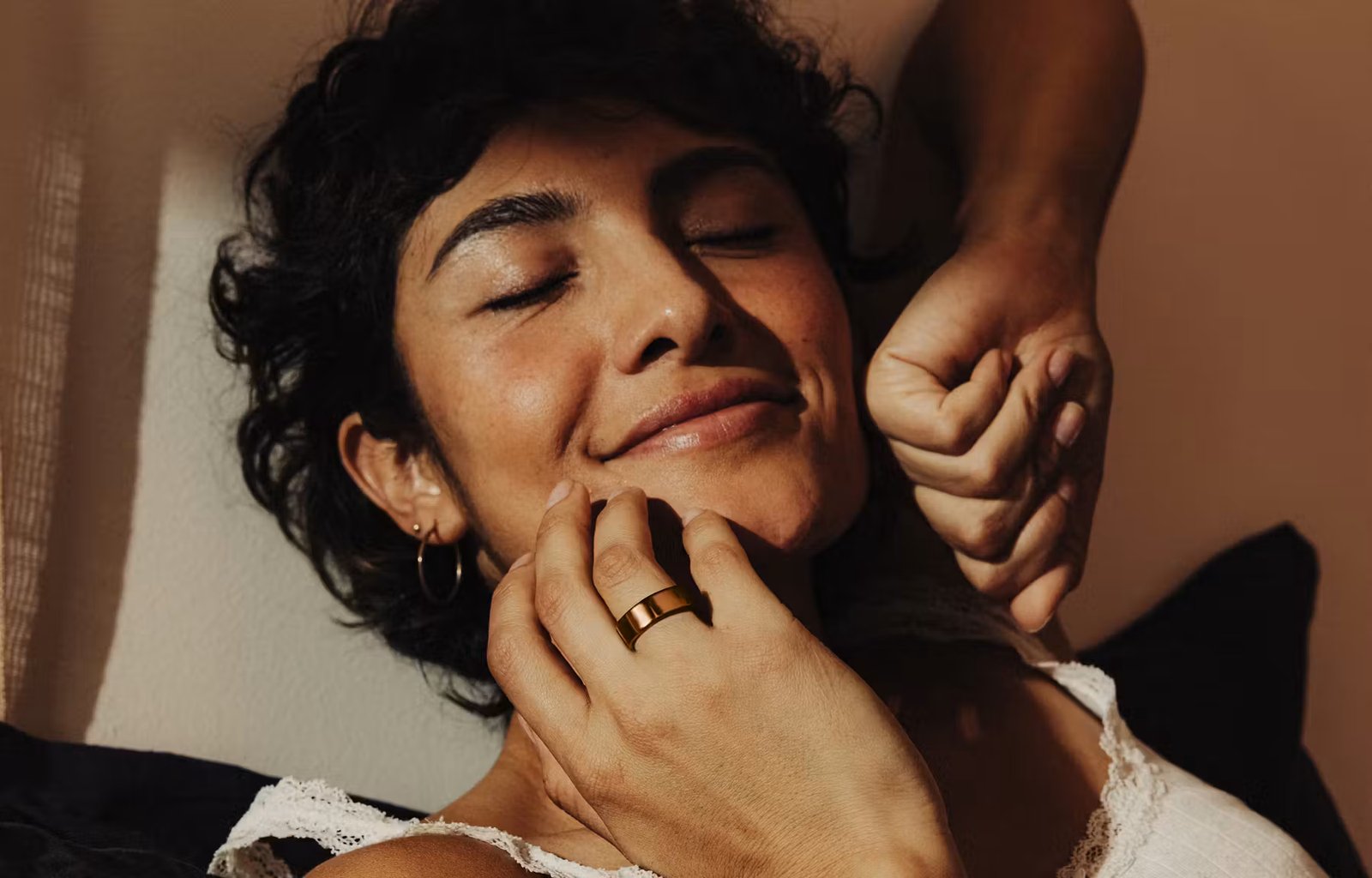 A close-up shot of a woman stretching with her hand near her face and an Oura Ring on her finger.
